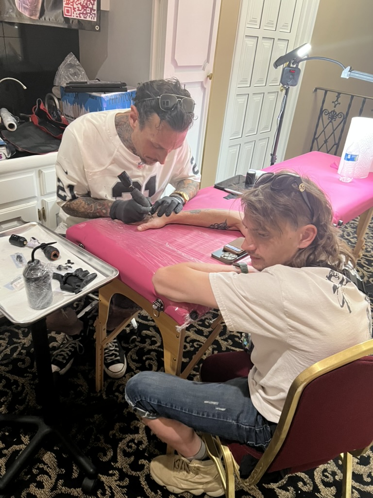 Joshua Cole reviewing tattoo designs with client at portable offsite station
