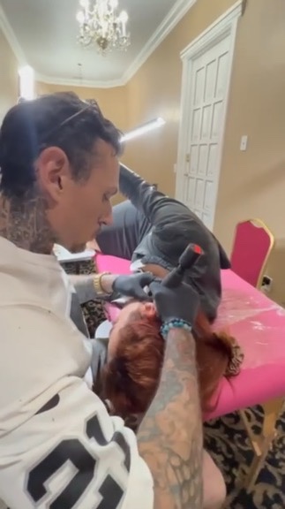 Joshua Cole tattoos woman's ear cartilage on pink table in chandelier-lit hotel suite — Joshua Cole offsite booking, Work of Art Las Vegas
