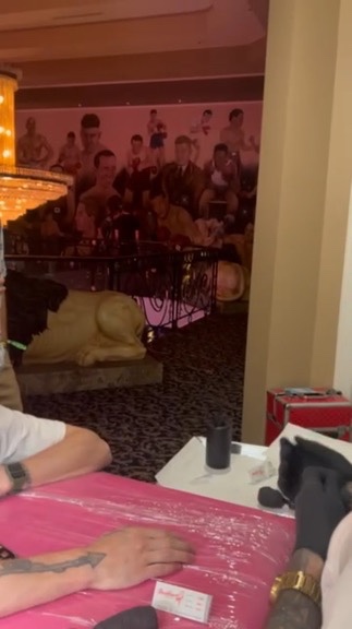 Arrow forearm tattoo on pink table beside lion statue and boxing mural at offsite — Joshua Cole offsite booking, Work of Art Las Vegas
