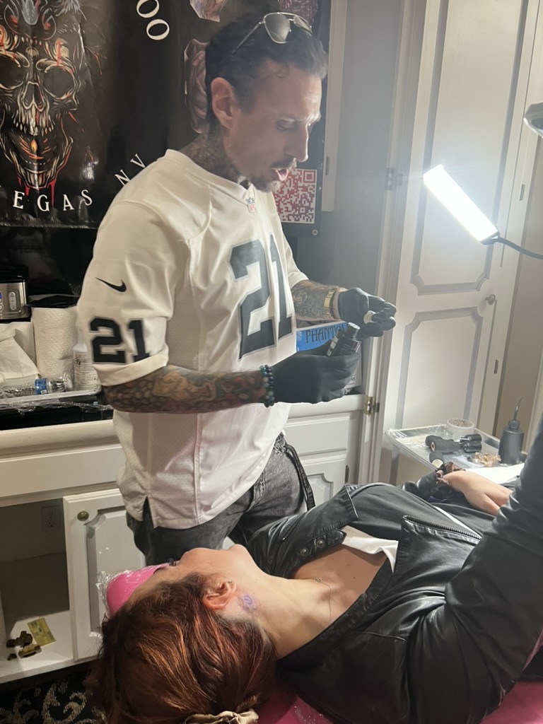 Joshua Cole opens ink bottle as client waits with purple neck stencil — Joshua Cole offsite booking, Work of Art Las Vegas