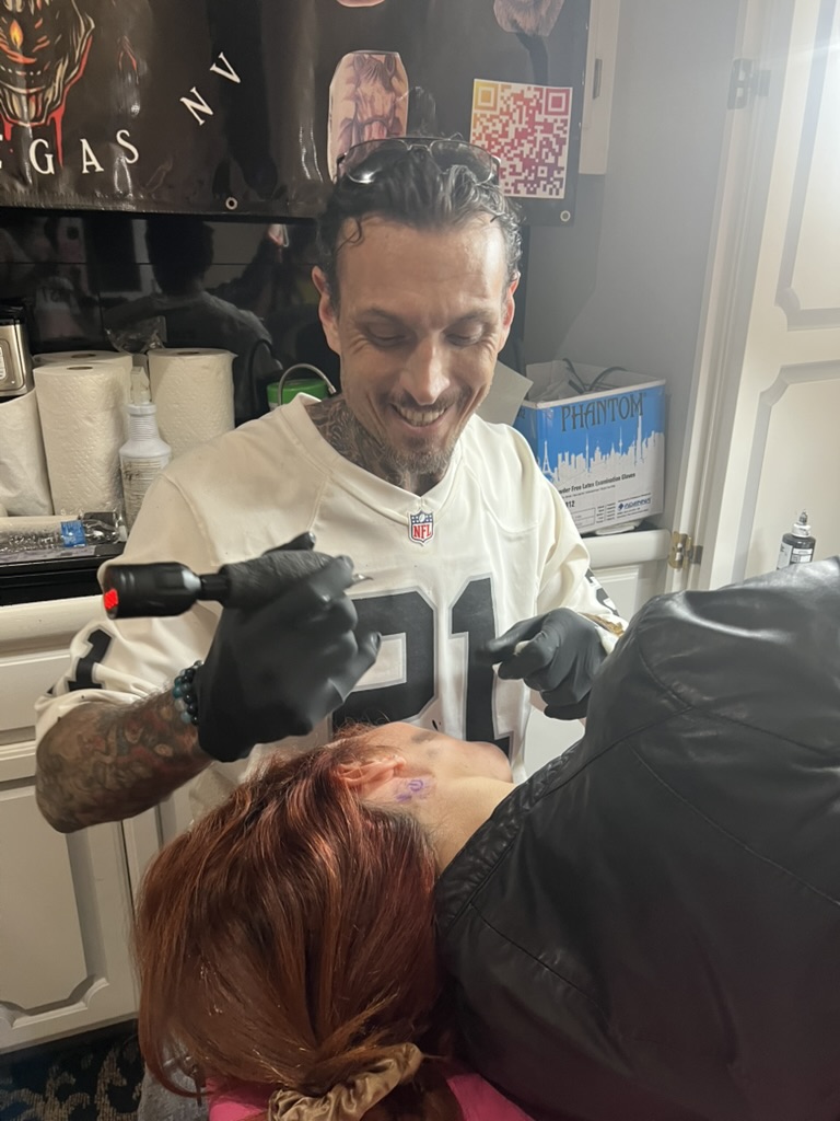 Joshua Cole smiles, machine ready behind client's ear stencil — Joshua Cole offsite booking, Work of Art Las Vegas