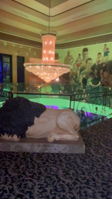 Lion statue overlooks boxing mural and chandelier in Vegas hotel mezzanine lounge — Joshua Cole offsite booking, Work of Art Las Vegas