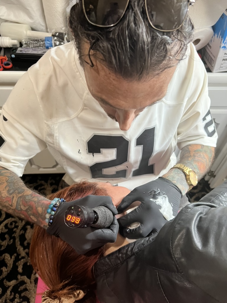 Overhead of Joshua Cole tattooing behind client's ear with rotary gun — Joshua Cole offsite booking, Work of Art Las Vegas