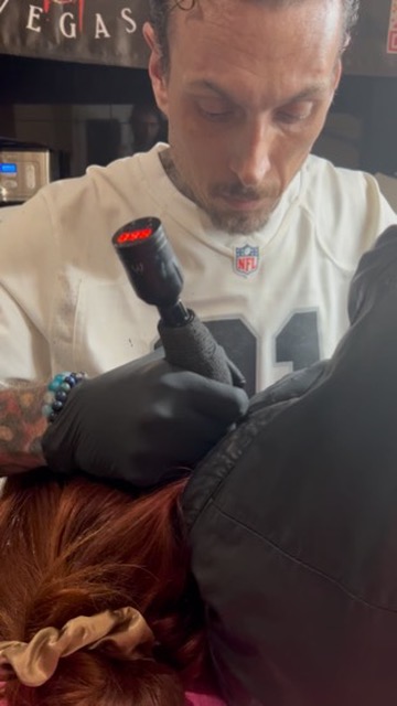 Joshua Cole tattoos power-button icon on neck behind client's ear at offsite event — Joshua Cole offsite booking, Work of Art Las Vegas