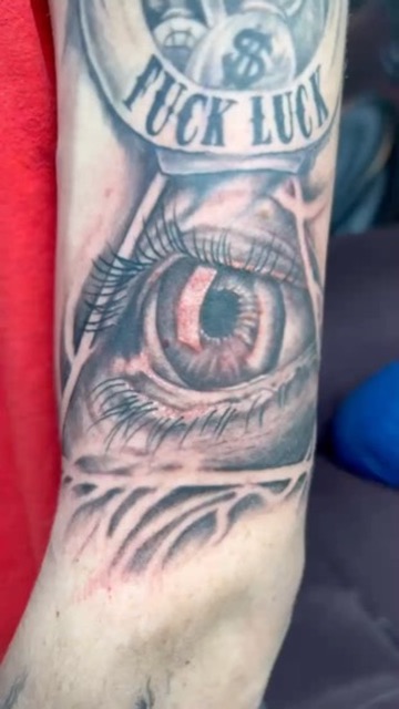 Black and grey all-seeing eye with FUCK LUCK banner and money bags on forearm. — Joshua Cole, Work of Art Las Vegas