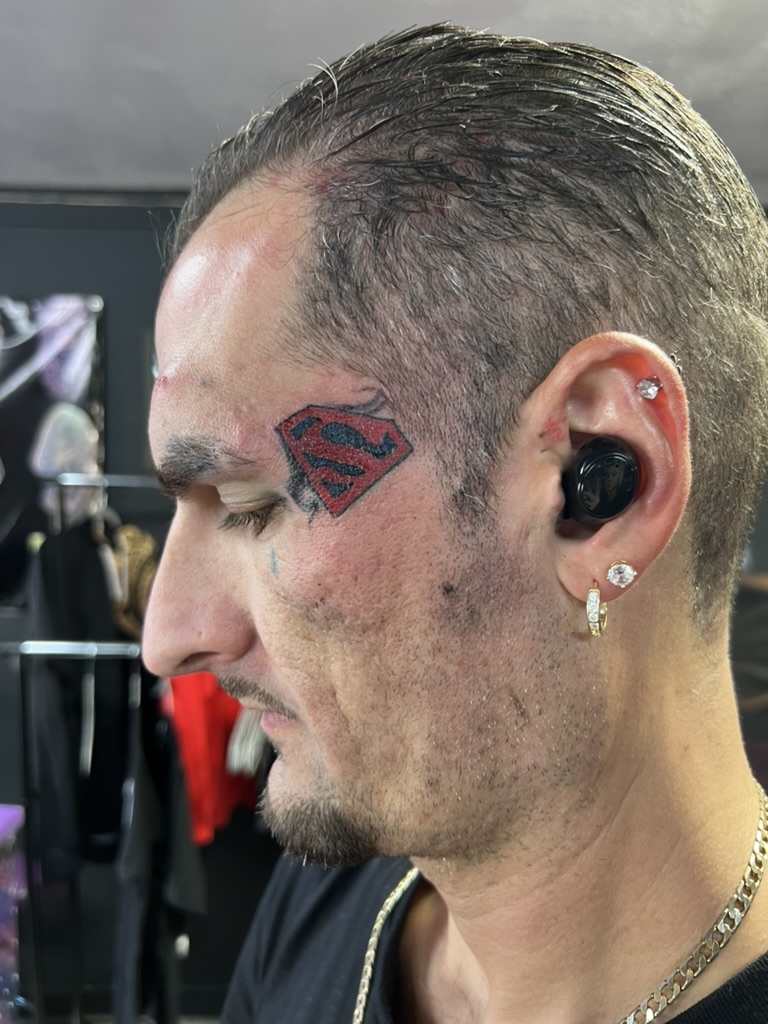 Color Superman S shield with smoke accents on left temple near eyebrow. — Joshua Cole, Work of Art Las Vegas