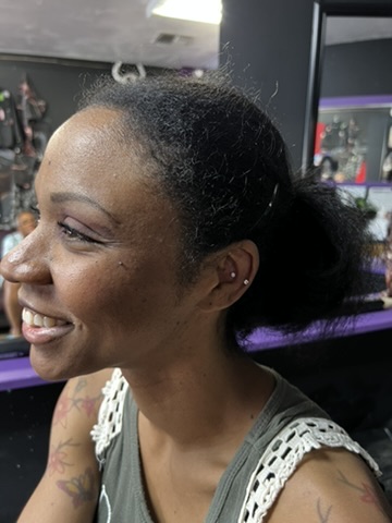 Smiling client showing fresh conch and lobe studs beside colorful butterfly shoulder tattoos — Joshua Cole, Work of Art Las Vegas