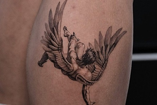Black-grey Icarus-style falling angel with spread feathered wings on leg, fine-line shading — Joshua Cole, Work of Art Las Vegas