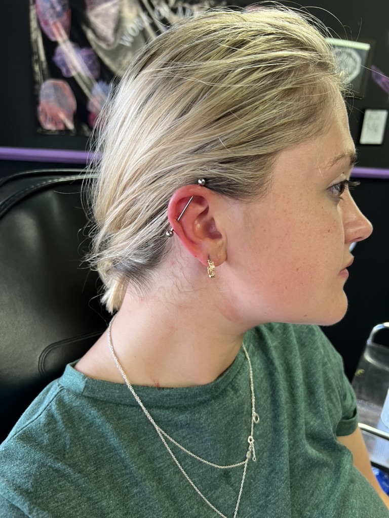 Blonde freckled client with silver industrial barbell and decorative gold lobe hoop earring — Joshua Cole, Work of Art Las Vegas