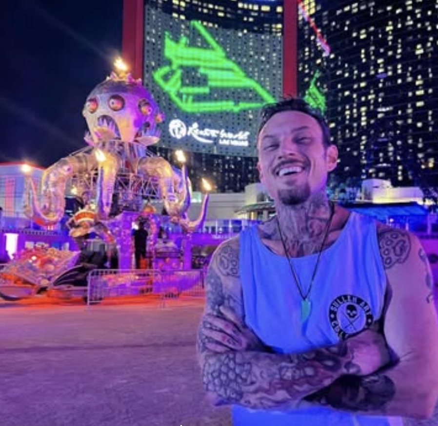 Joshua Cole at a fire-breathing octopus art car with Vegas skyline behind — Joshua Cole, Work of Art Las Vegas