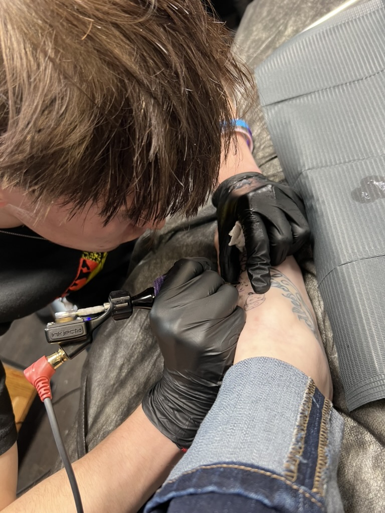 Joshua Cole applying a fine-line ankle tattoo with a rotary machine. — Joshua Cole, Work of Art Las Vegas