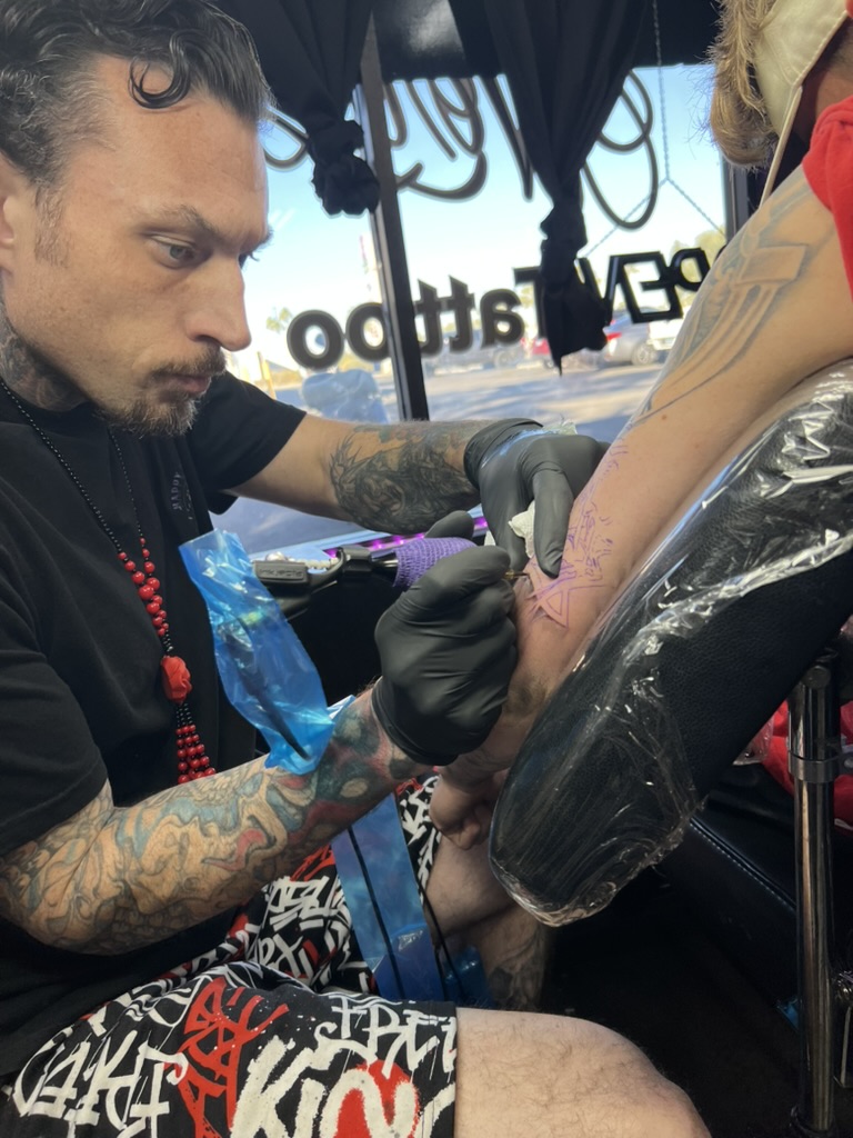 Joshua Cole inking a geometric star stencil on a client's forearm. — Joshua Cole, Work of Art Las Vegas