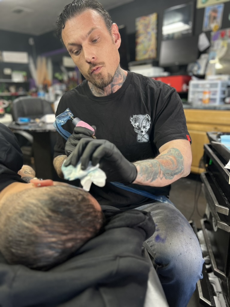 Joshua Cole carefully tattooing a client's temple during a head tattoo session. — Joshua Cole, Work of Art Las Vegas