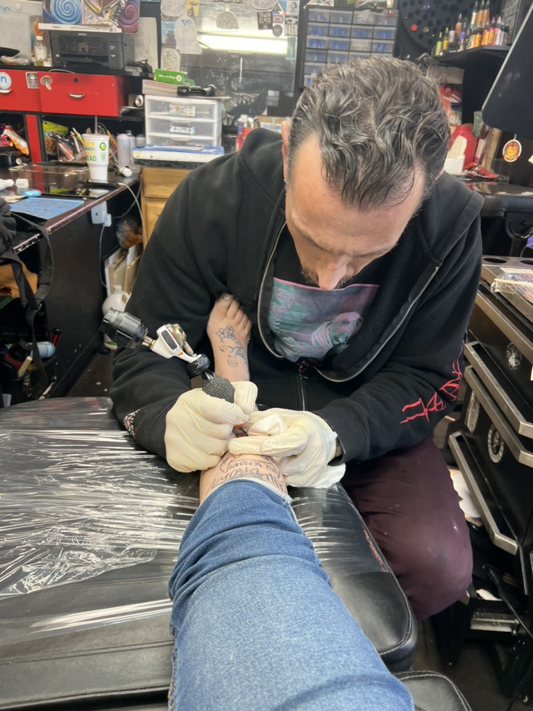 Joshua Cole tattooing illustrative demon and text piece — Work of Art Las Vegas studio
