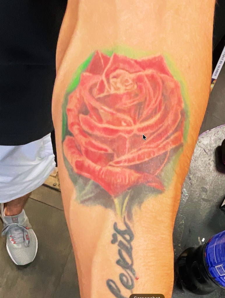 Color realism red rose with soft green halo and cursive Alexis script on inner forearm — Joshua Cole, Work of Art Las Vegas