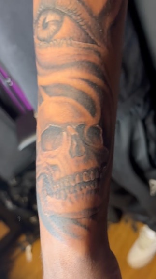 Black and grey realistic skull stacked beneath a detailed eye on the forearm. — Joshua Cole, Work of Art Las Vegas